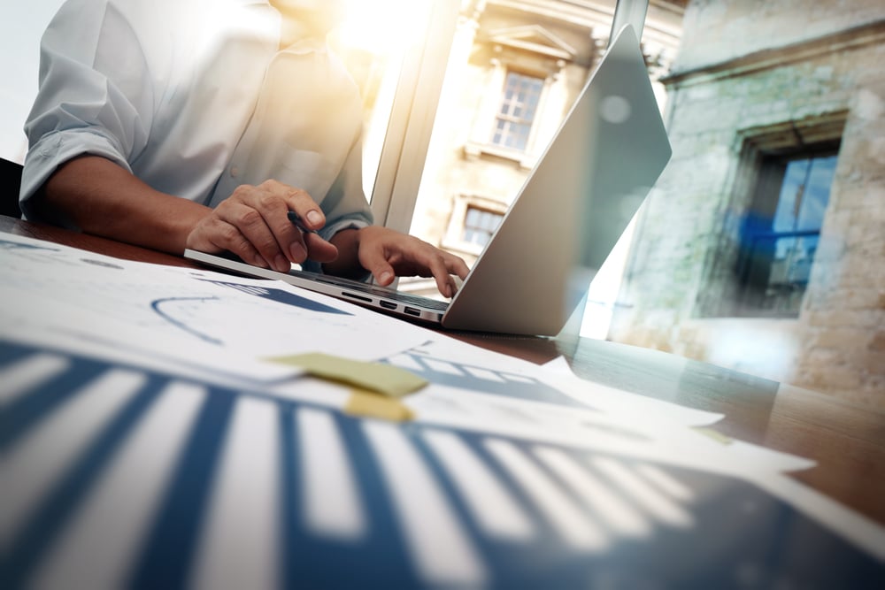 An employee creating and analysing financial reports on the laptop that is a part of CFO Services.