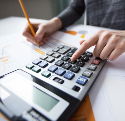 Close-up of hands using a calculator and reviewing financial documents, illustrating the cost-effective value of fractional CFO services.